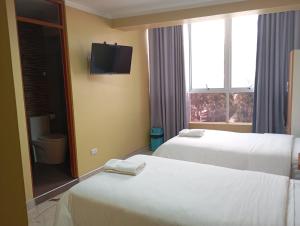 a hotel room with two beds and a window at Hotel ROYALS HUARAZ in Huaraz