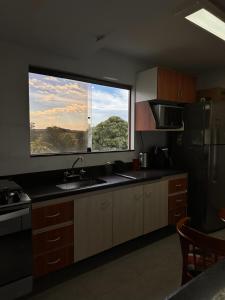 a kitchen with a sink and a large window at Pousada Jamacaii in Araxá