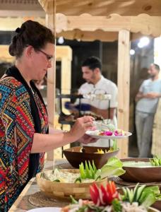 a woman holding a plate of food on a buffet at WADI RUM ROTANA BUBBLE lUXURY in Wadi Rum