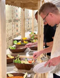 two men preparing food in a buffet line with bowls of food at WADI RUM ROTANA BUBBLE lUXURY in Wadi Rum +23 photos