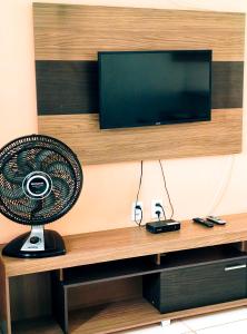 a television on a wall with a fan on a desk at Casas Bela da Chapada in Lençóis