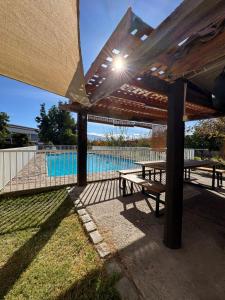 a wooden pergola with a picnic table and a pool at Hostal Almendral in San Felipe