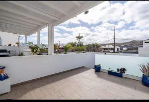 a white balcony with a white wall and plants at Volcán de la Corona House in Punta Mujeres