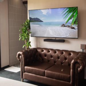 a brown leather couch in a room with a flat screen tv at Örök Landscape Hotel in Rionegro