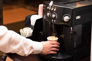 a man is holding a coffee cup in front of a coffee machine at Grand Park Hotel Odate in Odate