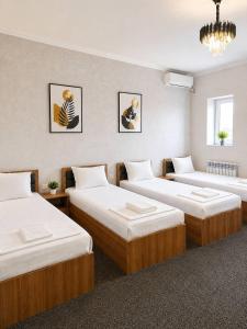 a room with three beds and a chandelier at Ameli Plaza Hotel Tashkent in Yakkasaray