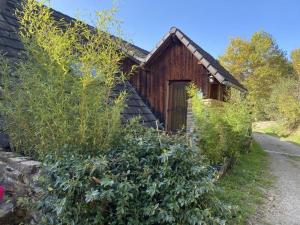 a wooden house with a bunch of bushes in front of it at La Bernadole - Chambres d'Hôtes in Aleu