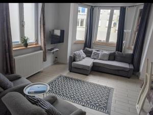 a living room with a couch and a tv at Appartement spacieux avec parking et terrasse in De Panne