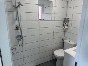a white tiled bathroom with a toilet and a shower at carmel cabins suite nu 9 in Yājur