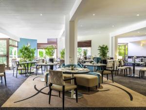 a restaurant with tables and chairs and windows at Mercure Maurepas Saint Quentin in Maurepas