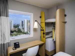 a room with a bed and a desk and a window at ibis Fortaleza Centro de Eventos in Fortaleza