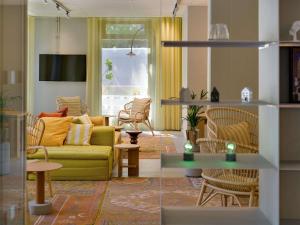 a living room with a yellow couch and chairs at ibis Leipzig City in Leipzig