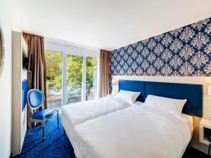 a hotel room with two beds and a window at ibis Styles Rastatt Baden-Baden in Rastatt