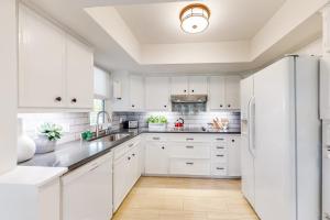 a white kitchen with white cabinets and a refrigerator at Peaceful Mid-Century Escape with Screened Porch & Lake Access in Lago Vista