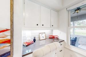 a white kitchen with white cabinets and a window at Peaceful Mid-Century Escape with Screened Porch & Lake Access in Lago Vista +23 photos