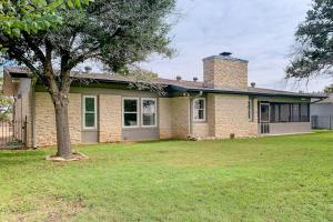 a brick house with a tree in the yard at Peaceful Mid-Century Escape with Screened Porch & Lake Access in Lago Vista