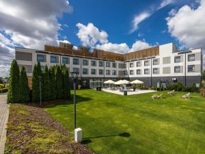 a large white building with a lawn in front of it at Ibis Poznan Polnoc in Suchy Las
