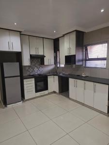 a kitchen with white cabinets and black appliances at Mafjoint6 in eMalahleni