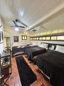 a bedroom with three beds and a ceiling fan at Hari Eco Pousada in Brumadinho
