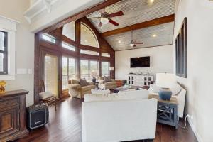 a living room with white furniture and a ceiling fan at Opulent Waterfront Home with Dock, Firepit & Stunning River View in Burnet