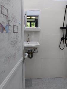 a white bathroom with a sink and a window at Raja Ampat Sandy Guest House in Saonek