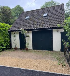 a detached garage with a black and white at Riverside Dormer Mells nr Babington in Frome