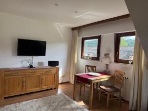 a living room with a dining room table and a television at Ferienwohnung mit großem Balkon und Blick in den Taunus in Oberems