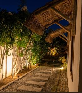 a walkway leading to a building with a straw umbrella at Bangalô Exclusivo Pontal do Maceió in Fortim