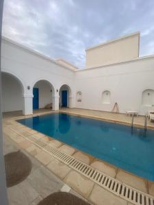 an indoor swimming pool with blue water in a white building at Menzel à Midoun in Al Maqārisah