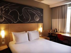 a hotel room with a large bed and a desk at ibis Yerevan Center in Yerevan +88 photos