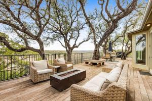a patio with a couch and chairs on a deck at Natural Cliffside Oasis with Impressive Views, Gas Fireplace and Dock in Spicewood