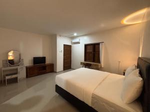 a bedroom with a white bed and a television at Jimbaran Hostel Bali in Jimbaran
