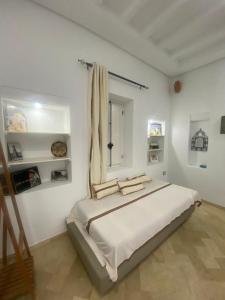 a white bedroom with a large bed and a window at Menzel à Midoun in Al Maqārisah +19 photos