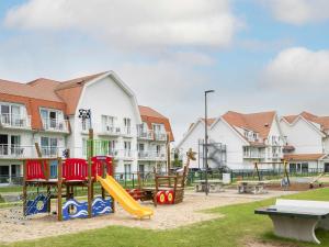 a playground with a slide in a park with buildings at ibis Styles Nieuwpoort in Nieuwpoort