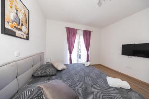 a bedroom with a bed and a flat screen tv at Ilma Apartment in Trogir