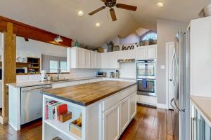 a large kitchen with white cabinets and a large island at Spacious Lakefront Hideaway with Decks, Grill, Billiards, Tennis & Pool in Spicewood