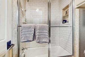 a bathroom with a shower with towels and a tub at Refined Panoramic Paradise on Lake Travis with Boat Launch and Tesla Charger in Spicewood +19 photos