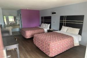 two beds in a hotel room with purple walls at Relax Inn Hotel in Birmingham +15 photos