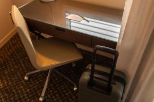 a desk with a chair and a desk with a suitcase at Point Hotel in Brisbane