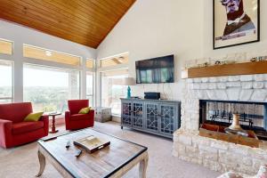 a living room with a stone fireplace and red chairs at Regal Riverfront Home with 2 Cabins - 2 Miles to Marina in Spicewood