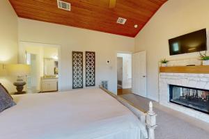 a bedroom with a white bed and a fireplace at Regal Riverfront Home with 2 Cabins - 2 Miles to Marina in Spicewood