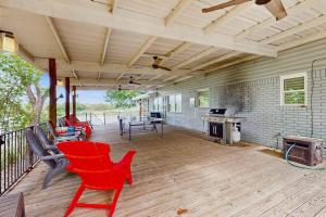 a porch with red chairs and a table and a stove at Waterfront Home with Kayaks, Game Room, Firepit, & Enormous Deck in Kingsland
