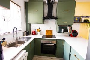 a kitchen with green cabinets and a sink at KADESE Holiday North Beach Durban in Durban