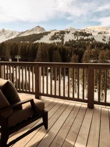 a chair on a deck with a view of mountains at Rosewood Courchevel Le Jardin Alpin in Courchevel