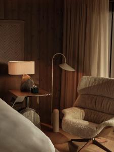 a bedroom with a bed and a chair and a lamp at Rosewood Courchevel Le Jardin Alpin in Courchevel +2 photos