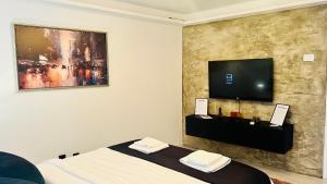 a bedroom with a bed and a flat screen tv on a wall at Escapist Apartments in Niš