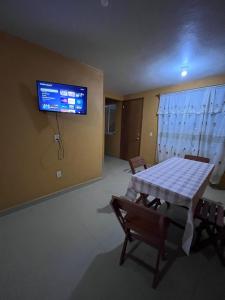 Ein Zimmer mit Tisch, Stühlen und einem Fernseher an der Wand. in der Unterkunft Rincón acogedor in Toluca de Lerdo + 8 Fotos