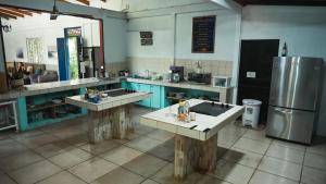 a large kitchen with two sinks and a refrigerator at Hostel Nosara in Playa Guiones