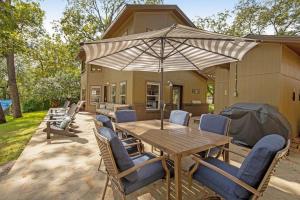 a wooden table with chairs and an umbrella on a patio at Two-Story Waterfront Retreat with Boat Dock, Two Firepits & Two Kayaks in Burnet