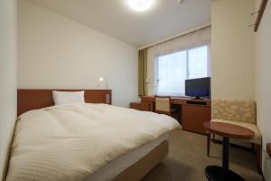 a hotel room with a bed and a television at Grand Park Hotel Odate in Odate